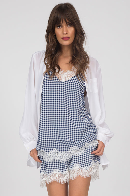 Model is wearing the Anne Marie Silk Cami in navy with an open white button up shirt and the Anne Marie Silk Shorts in navy/off white.