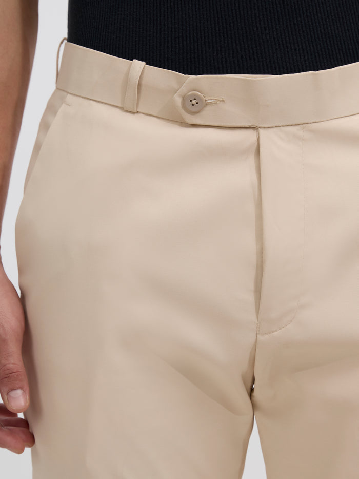 men's sand beige skinny fit trousers blended with polyster and spandex - paired with a black top and black shoes.