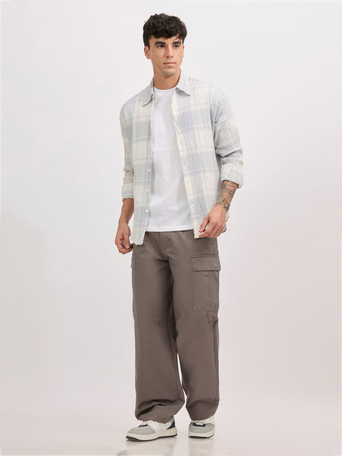 Men's oversized pale blue checkered cotton shirt with full sleeves, styled with grey trousers – casual fashion look
