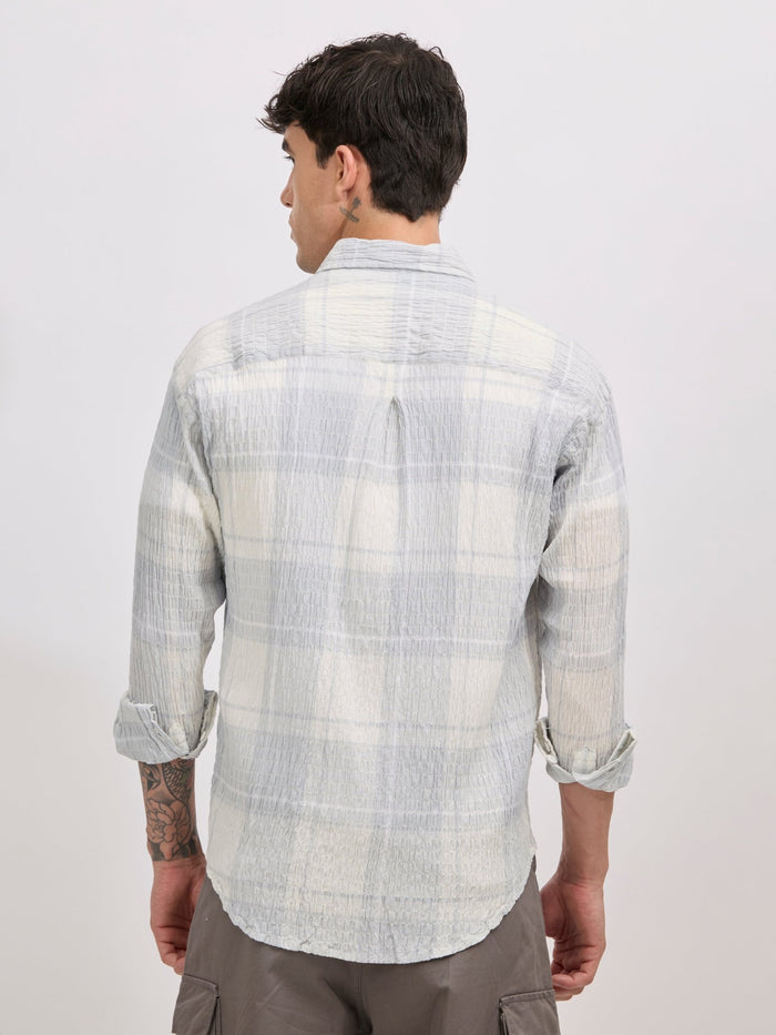 Men's oversized pale blue checkered cotton shirt with full sleeves, styled with beige trousers – casual fashion look