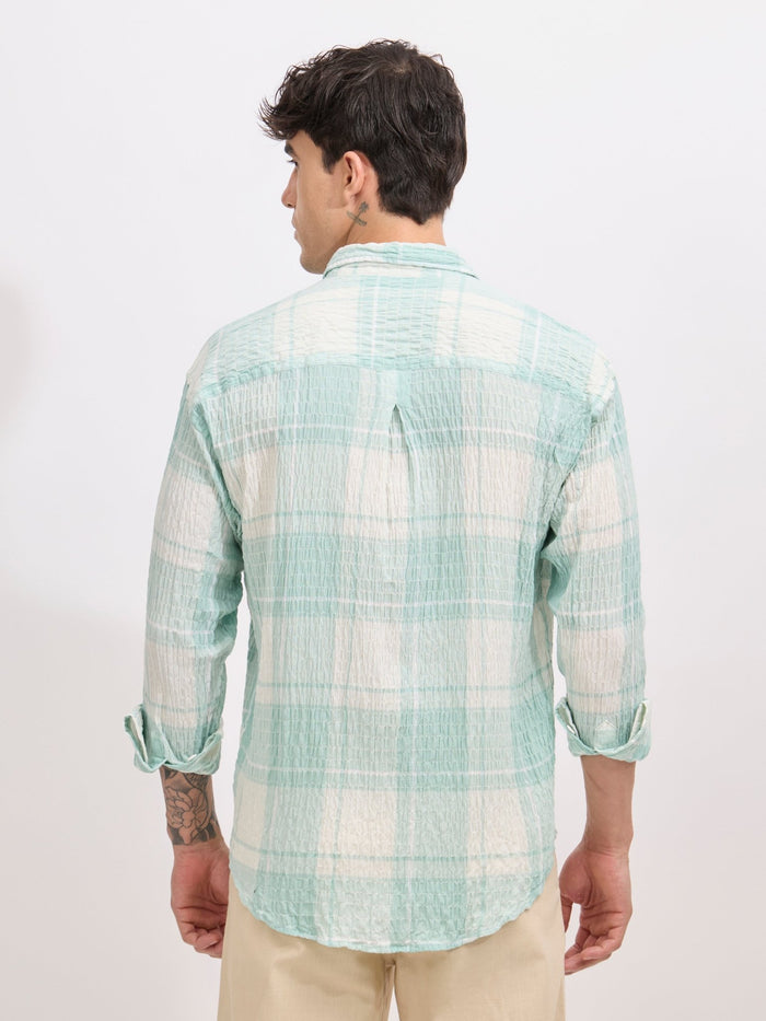 Men's oversized pale green checkered cotton shirt with full sleeves, styled with beige trousers – casual fashion look
