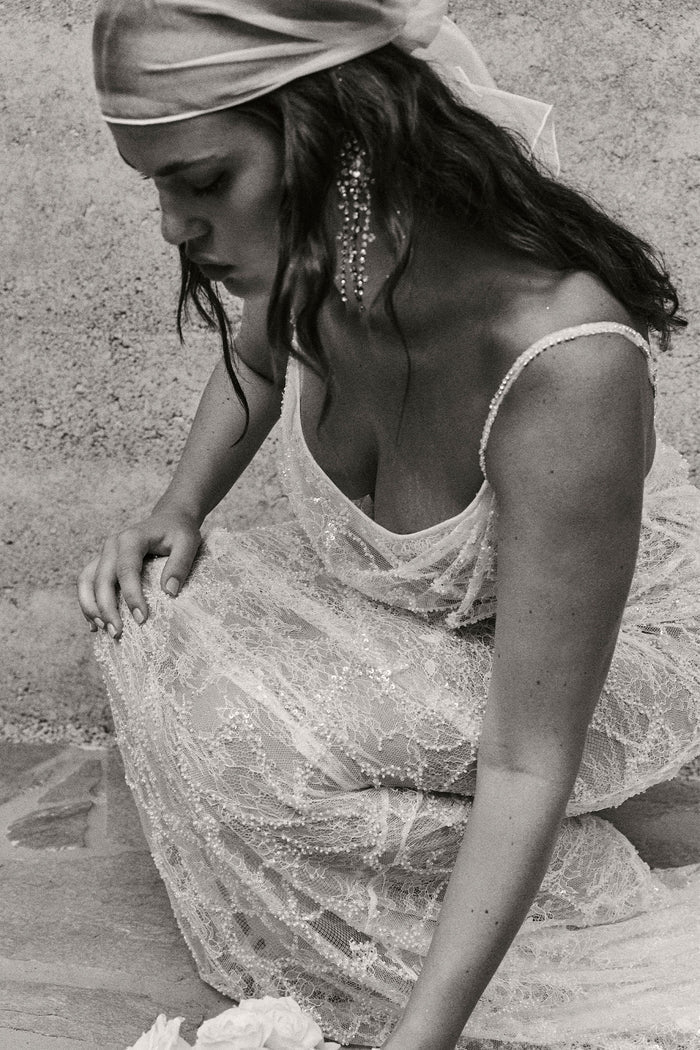 A woman in a lace wedding dress and headscarf.