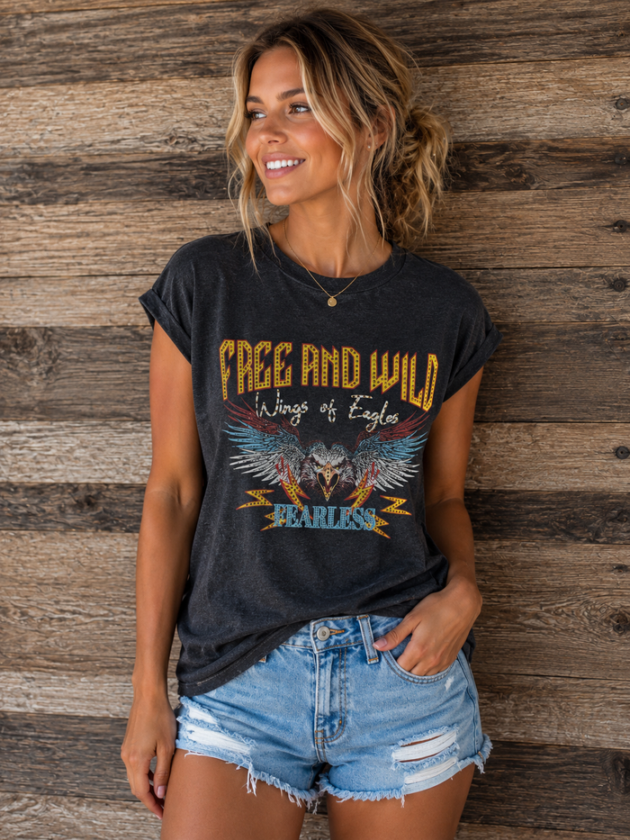 Woman wearing a black t-shirt with an eagle design and text, standing against a wooden wall.