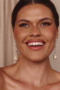 Woman wearing pearl earrings with a neutral background