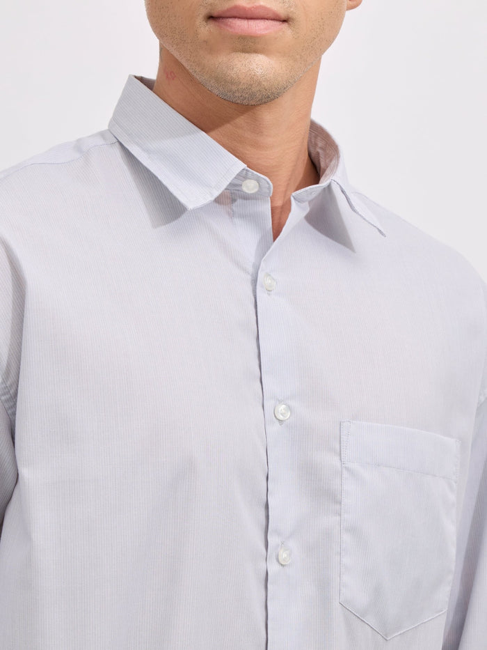 Man wearing grey cotton oversized striped shirt with rolled sleeves, front pocket, and button-down collar
100% cotton