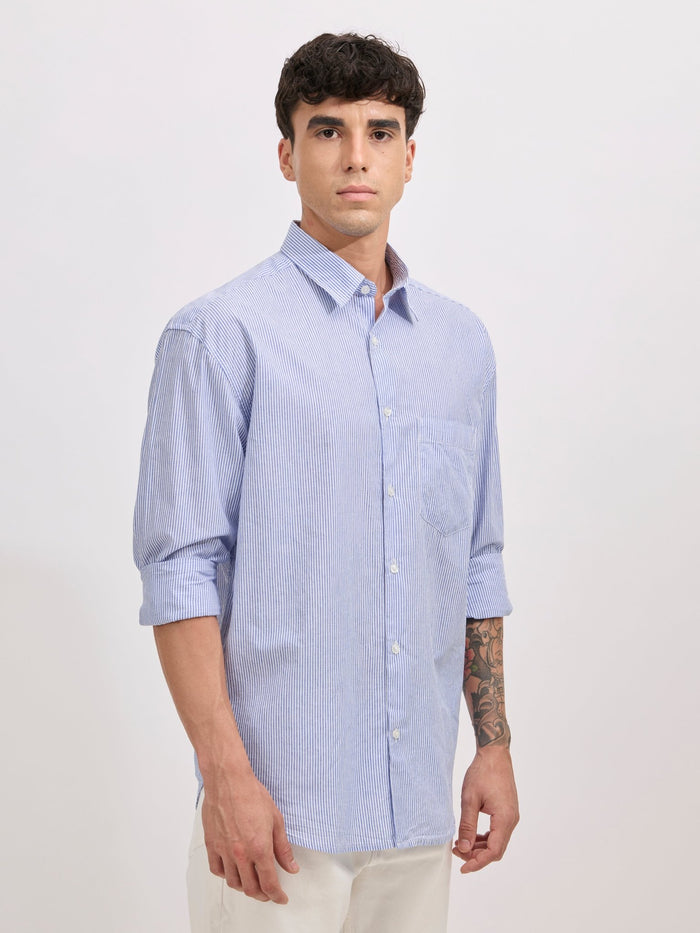 Man wearing sky blue cotton oversized striped shirt with rolled sleeves, front pocket, and button-down collar
100% cotton